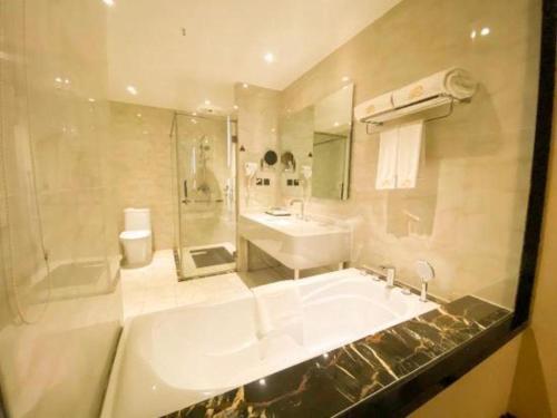 a bathroom with a tub and a sink and a shower at Pacific Regency Hotel Shenyang in Shenyang