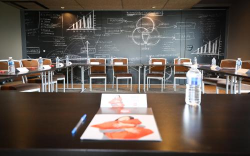 a classroom with tables and chairs and a bottle of water at Ibis Niort Est Mendes France in Niort