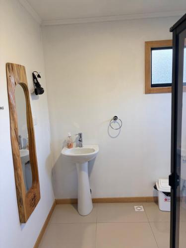 a white bathroom with a sink and a mirror at Cabaña Nahuelbuta Adventure in Cañete