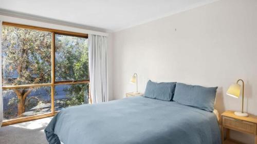 a bedroom with a bed and a large window at Ocean Ridge House Fairhaven in Aireys Inlet