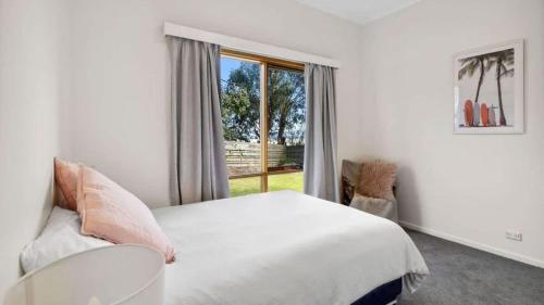 a white bedroom with a bed and a window at Ocean Ridge House Fairhaven in Aireys Inlet