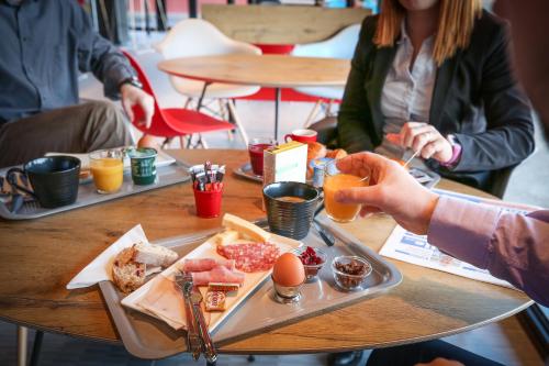 a group of people sitting at a table with a tray of food at Ibis Niort Est Mendes France in Niort