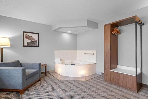 a room with a tub and a couch and a chair at AmericInn by Wyndham Sauk Centre in Sauk Centre