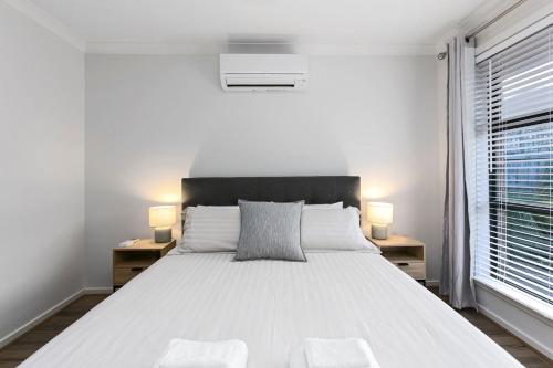 a white bedroom with a large bed with two night stands at Merihaven in Apollo Bay