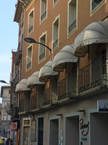 an apartment building with white balconies on a street at Hostal Pirineos in Barbastro