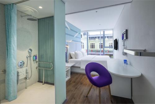 a bathroom with a bed and a purple chair in a room at Tru by Hilton Lao Cai City Riverside in Lao Cai