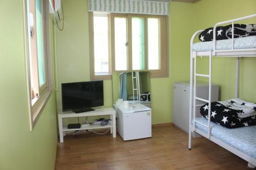 a room with two bunk beds and a television at Dadam Guesthouse in Yeosu