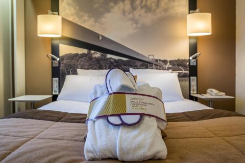 a stuffed animal is sitting on top of a bed at Mercure Cergy Pontoise Centre in Cergy