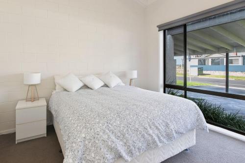 a white bedroom with a bed and a large window at Beachside Villa in Apollo Bay
