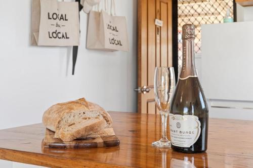 a bottle of wine and a loaf of bread on a table at Beachfront Apartment at Apollo in Apollo Bay