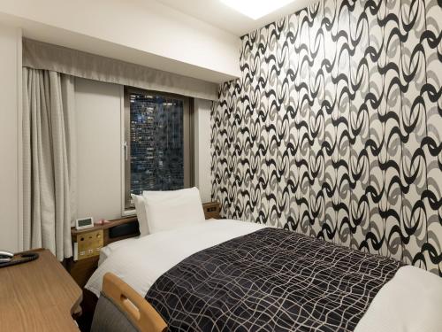 a bedroom with a bed with a black and white patterned wall at APA Hotel Osaka Higobashi Ekimae , All Rooms Non-Smoking in Osaka