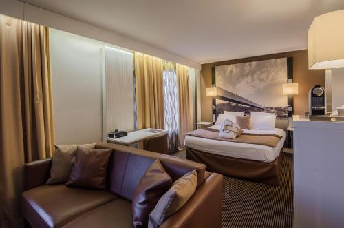 a hotel room with two beds and a couch at Mercure Cergy Pontoise Centre in Cergy