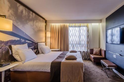 a hotel room with a large bed and a chair at Mercure Cergy Pontoise Centre in Cergy