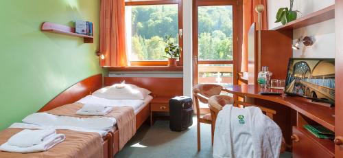 Cette chambre comprend deux lits, un bureau et une fenêtre. dans l'établissement Hotel Flóra, à Trenčianske Teplice