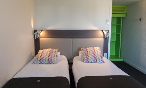 two beds in a small room with two white beds at Campanile Agen in Agen