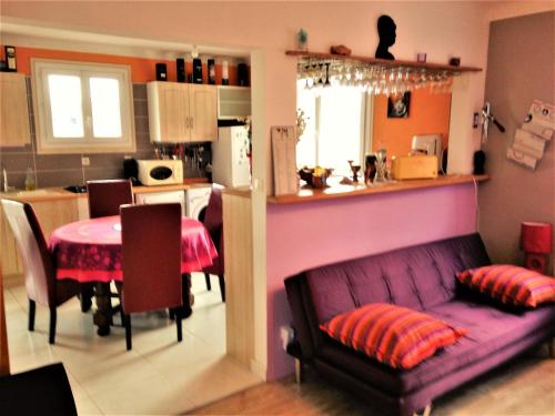 sala de estar y cocina con sofá púrpura y mesa en Maison au centre de Camazen, en Pludual