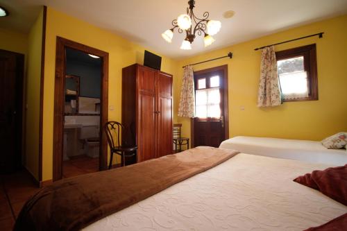 a bedroom with yellow walls and a bed and a chandelier at Hotel Rural Alavera in San Martin del Mar