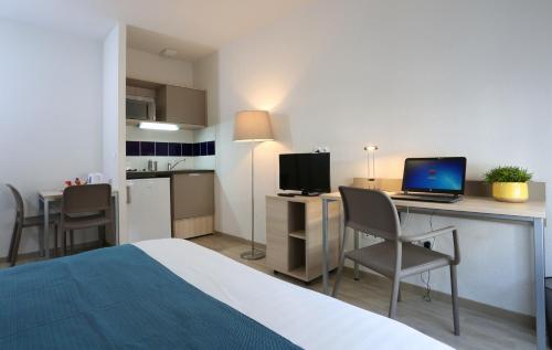 Habitación de hotel con cama y escritorio con ordenador portátil en Apparteo Nancy en Nancy