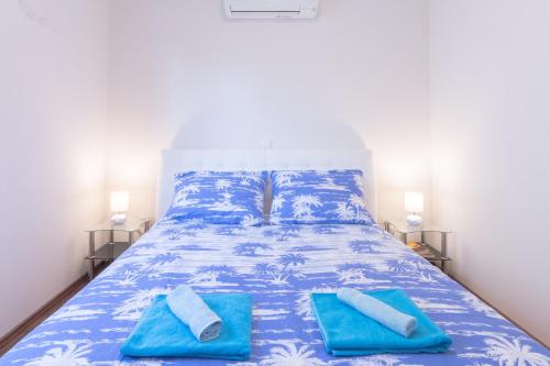 a bed with blue sheets and blue towels on it at Mladinic Palace in Milna