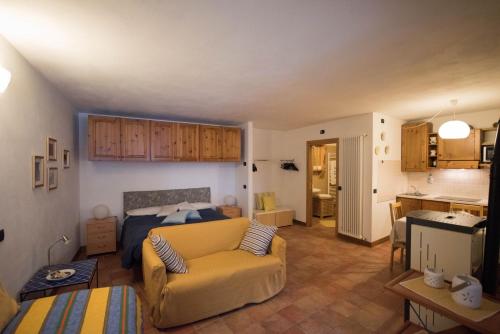 a living room with a yellow couch and a kitchen at Baita de Eliseo B&B in Valdisotto