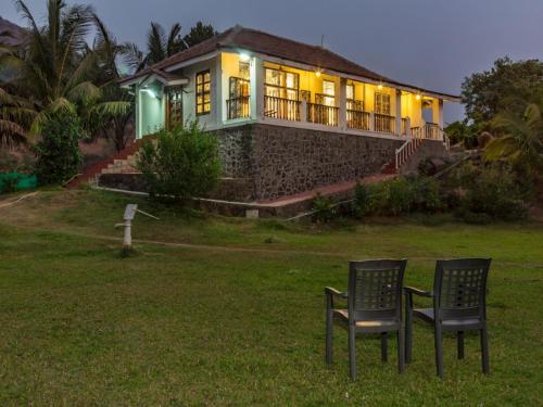 two chairs in front of a house at night at SaffronStays Salt Rim on the Beach, Korlai in Christpāda