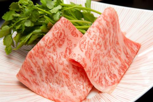 a white plate with two pieces of meat and greens at 旅館かわな -Ryokan Kawana- in Kimitsu