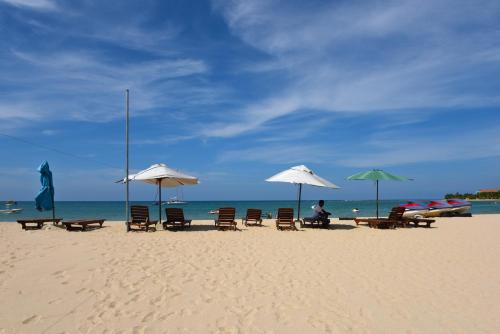 a group of chairs and umbrellas on a beach at Marina Beach Passikudah in Pasikuda