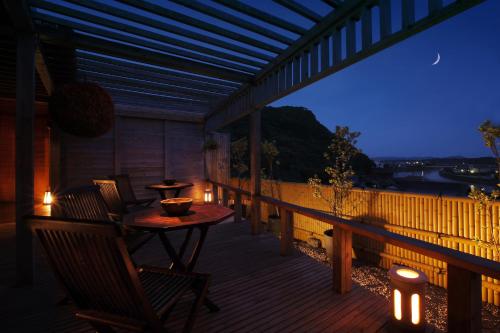 a porch with a table and chairs on a deck with lights at 旅館かわな -Ryokan Kawana- in Kimitsu
