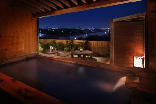a swimming pool with a table on a balcony at night at 旅館かわな -Ryokan Kawana- in Kimitsu