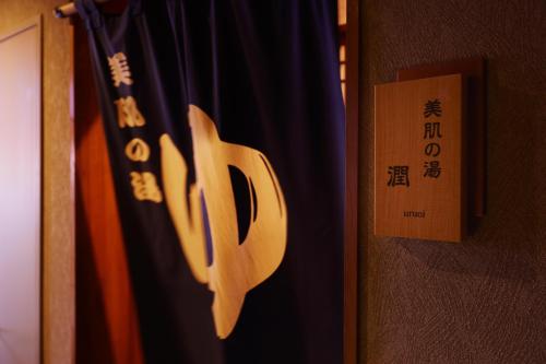a door with a wooden sign next to a curtain at 旅館かわな -Ryokan Kawana- in Kimitsu