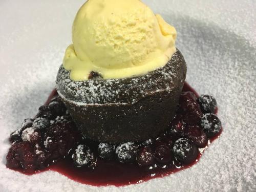 a chocolate dessert with a scoop of ice cream and berries at Pension & Restaurant Atmosféra in Loket