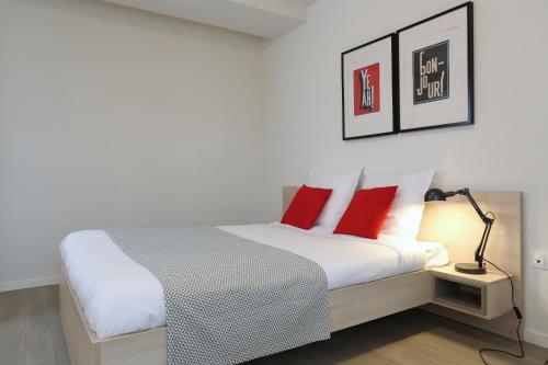 a bedroom with a bed with red pillows and a lamp at Apparteo Nancy in Nancy