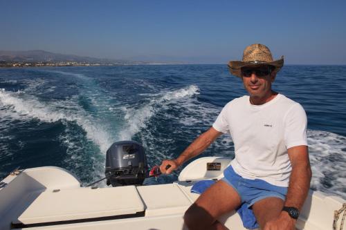 a man in a hat sitting on a boat at Oasis Scaleta Hotel in Skaleta