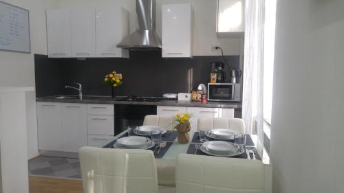uma cozinha com armários brancos e uma mesa com três pratos em Apartments Zagreb Center em Zagreb