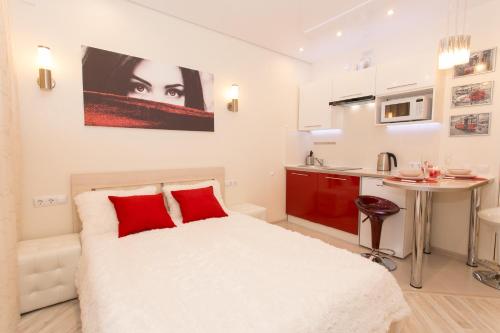 ニジニ・ノヴゴロドにある5days-nn, Studio apartment on Burnakovskaya 93のベッドルーム1室(白いベッド1台、赤い枕、テーブル付)