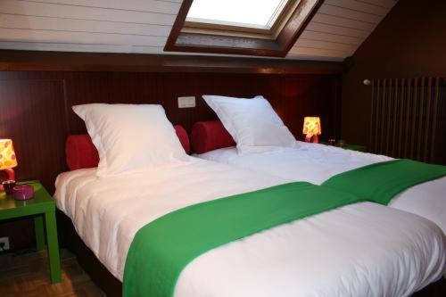 a bedroom with two beds with white and green sheets at Full House Hotel in Kortrijk