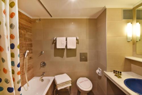 a bathroom with a tub and a toilet and a sink at Marina Alimos Hotel Apartments in Athens