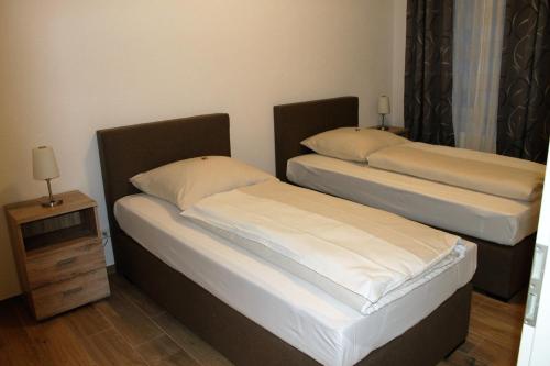 two twin beds in a room with a night stand at Ferienwohnungen Tannenhof in Steinen