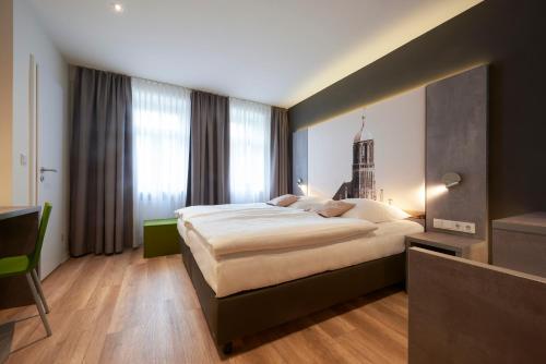 a bedroom with a large bed and a large window at Hotel VICTORIA Nürnberg in Nürnberg