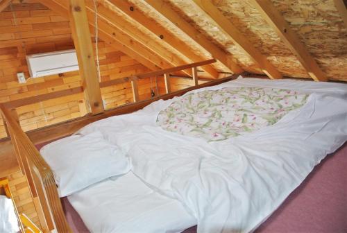 a large white bed in a wooden cabin at Pension Megumiyuki in Biei