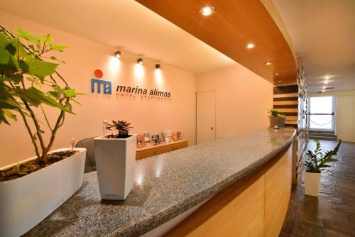 an office lobby with a counter with plants on it at Marina Alimos Hotel Apartments in Athens