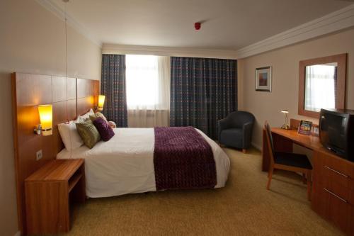 a hotel room with a bed and a desk and a television at Britannia Hotel Bolton in Bolton