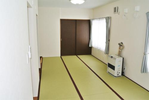 an empty room with a hallway with green floors and a door at Pension Megumiyuki in Biei