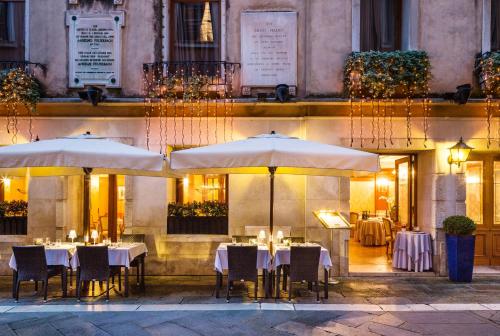 威尼斯的住宿－露納巴廖尼酒店– 立鼎世酒店集團，大楼前的餐厅,配有桌子和遮阳伞