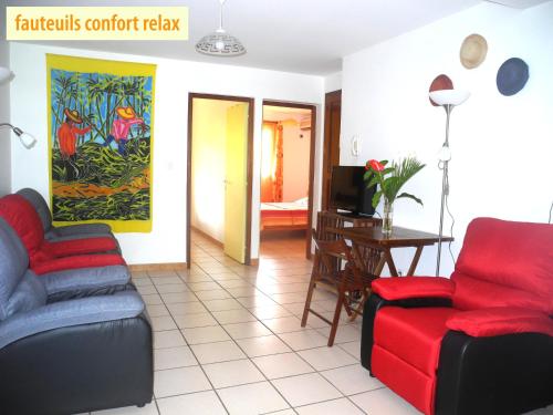 a living room with two chairs and a table at Les Hibiscus de la Rivière in Saint-Louis