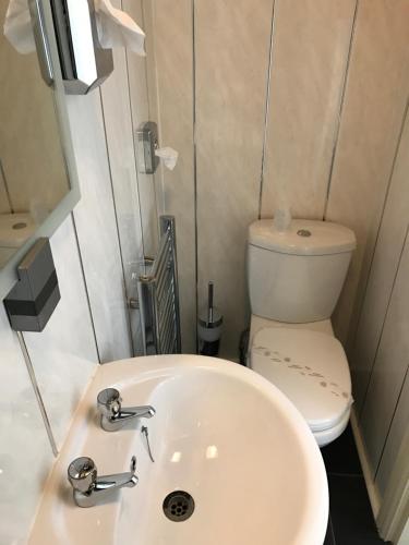 a bathroom with a white sink and a toilet at Queens Plaza Hotel in Blackpool