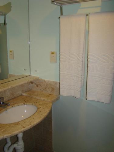 a bathroom with a sink and a shower with towels at Divi-Divi Praia Hotel in Natal