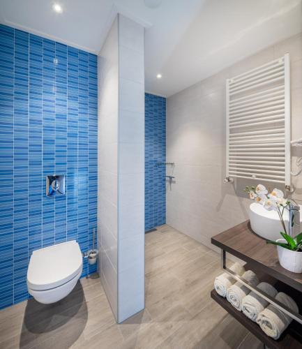 a bathroom with a toilet and a sink and blue tiles at Hotel bij Boone in Meliskerke