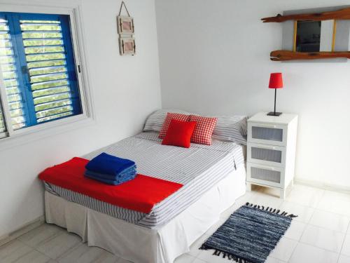 een kleine slaapkamer met een bed met rode en blauwe kussens bij Ikaria Village Studio in Paphos City