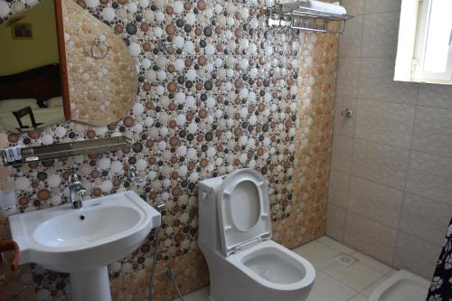 a bathroom with a sink and a toilet and a mirror at Green Mountain Hotel Apartments in Al ‘Aqar